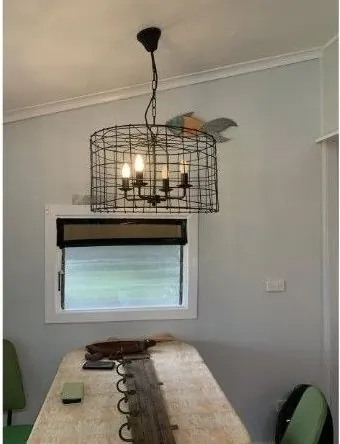 Black cage pendant light hanging over a dining table