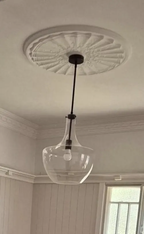 Glass pendant light hanging from a decorative ceiling rose