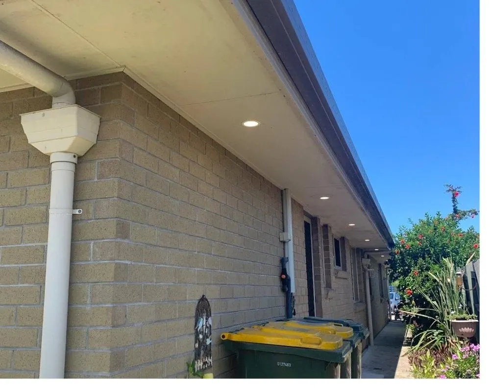 LED downlights installed in the eaves along the side of a brick home